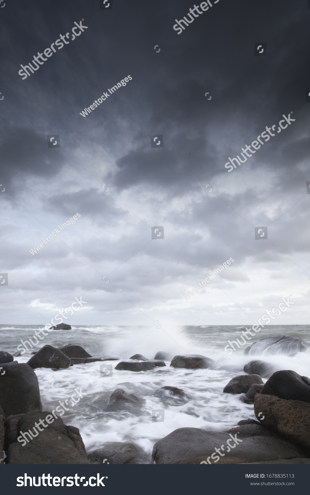 Wellen schlagen gegen Felsen unter Wolkenhimmel
