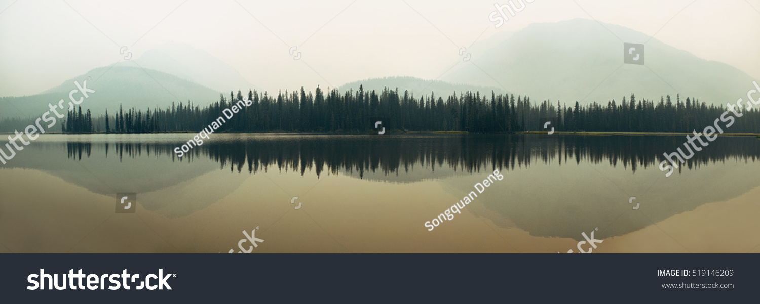 Nebeliger See mit Berg- und Waldspiegelung als abstrakte Landschaft